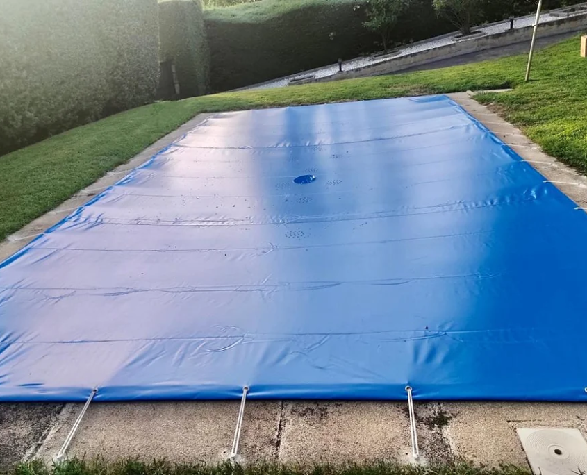 Lona azul extendida sobre una piscina, utilizada para el cierre seguro y la protección del agua y la estructura.